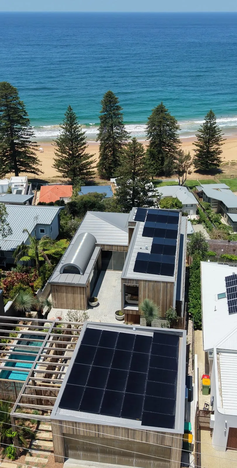 Solar panels across the roof levels of a timber-clad coastal home