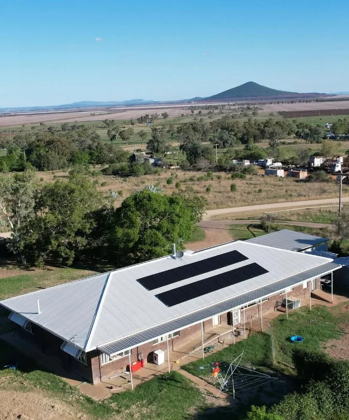 Aerial view of a country home with rooftop solar, hills in the distance